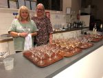 Karen and Joanne in Kitchen at wine tasting 13 October 2023 with lots of glasses of wine ready for serving